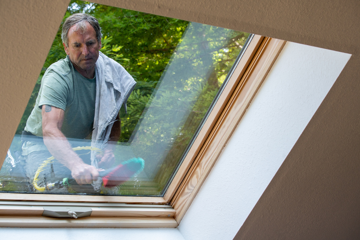 Man washing skylight on roof of house Man washing skylight on roof of house in California