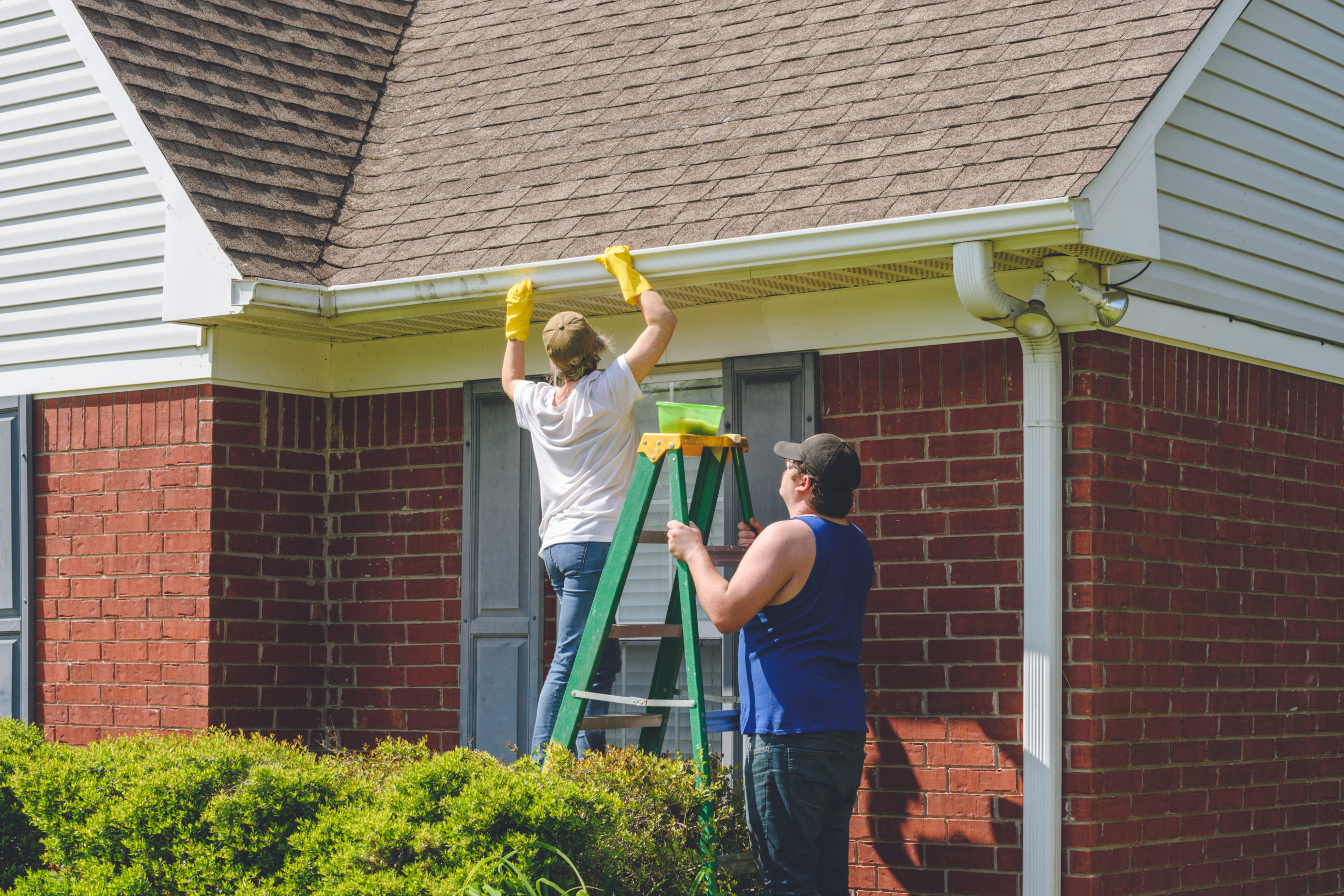 man on roof cleaning gutters.